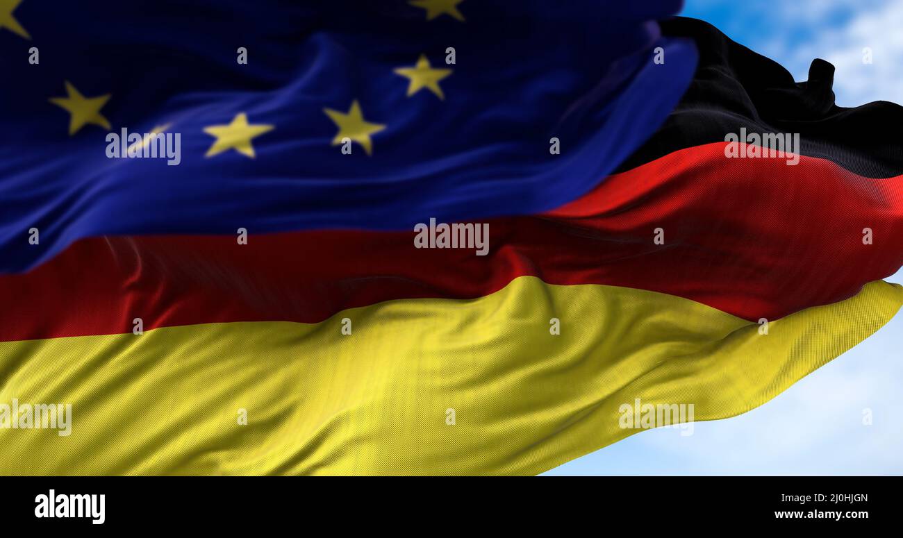 La bandiera nazionale della Germania che sventola nel vento insieme alla bandiera dell'Unione europea si è offuscata in primo piano Foto Stock
