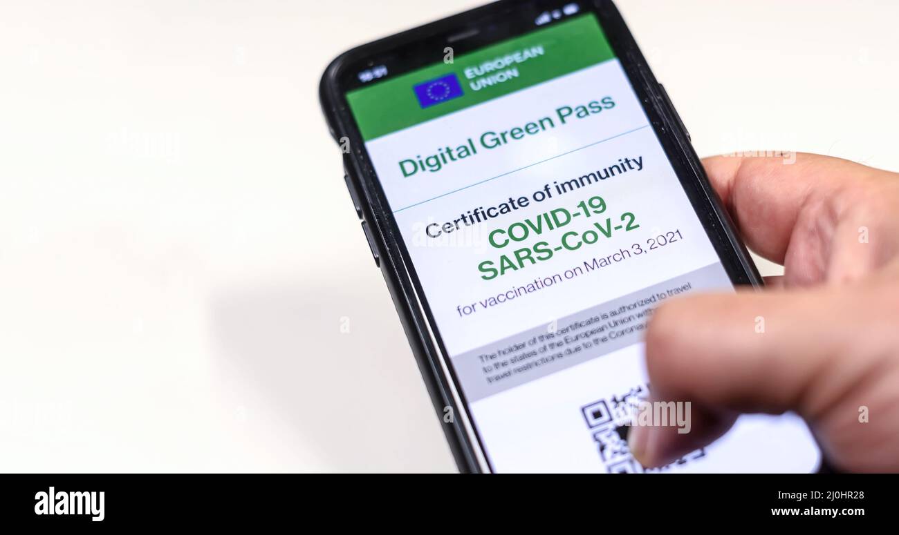 Il passo verde digitale dell'Unione europea con il codice QR sullo schermo di un cellulare tenuto da una mano Foto Stock