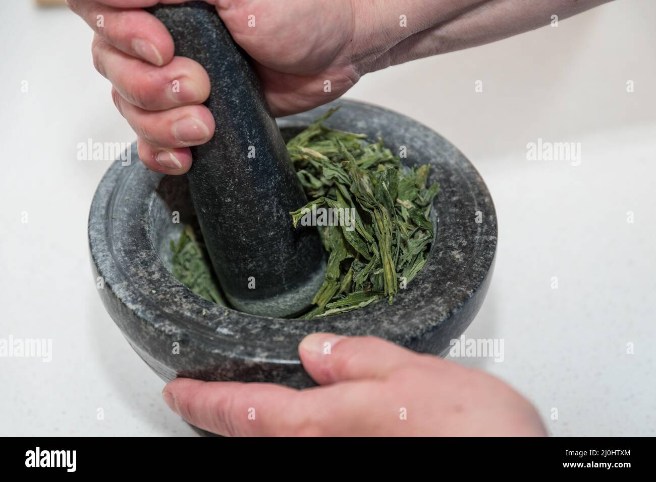 Macinare l'aglio selvatico in un mortaio con pestello - primo piano delle erbe medicinali Foto Stock