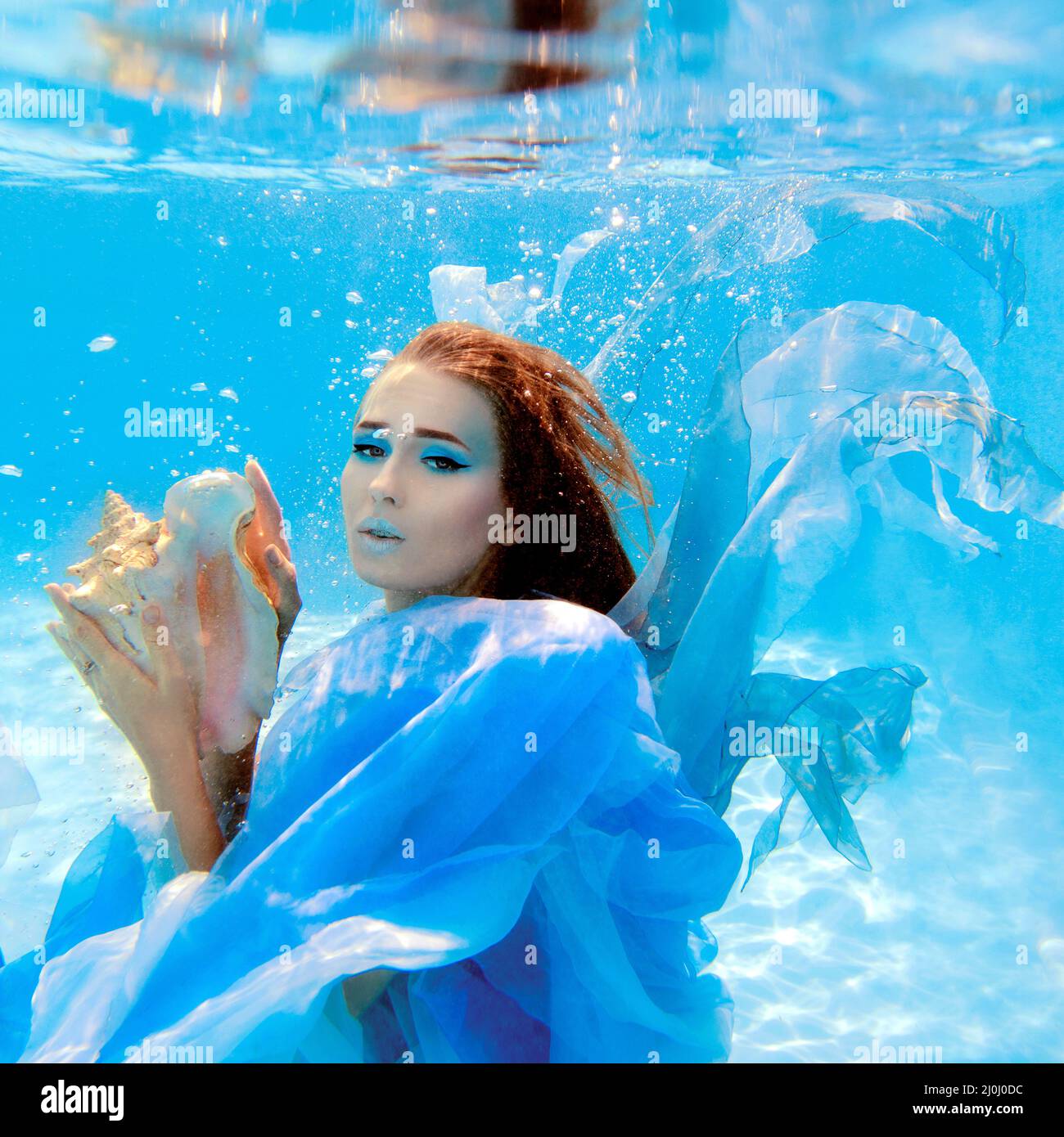 Ritratto subacqueo di moda di bella giovane donna in abito blu Foto Stock