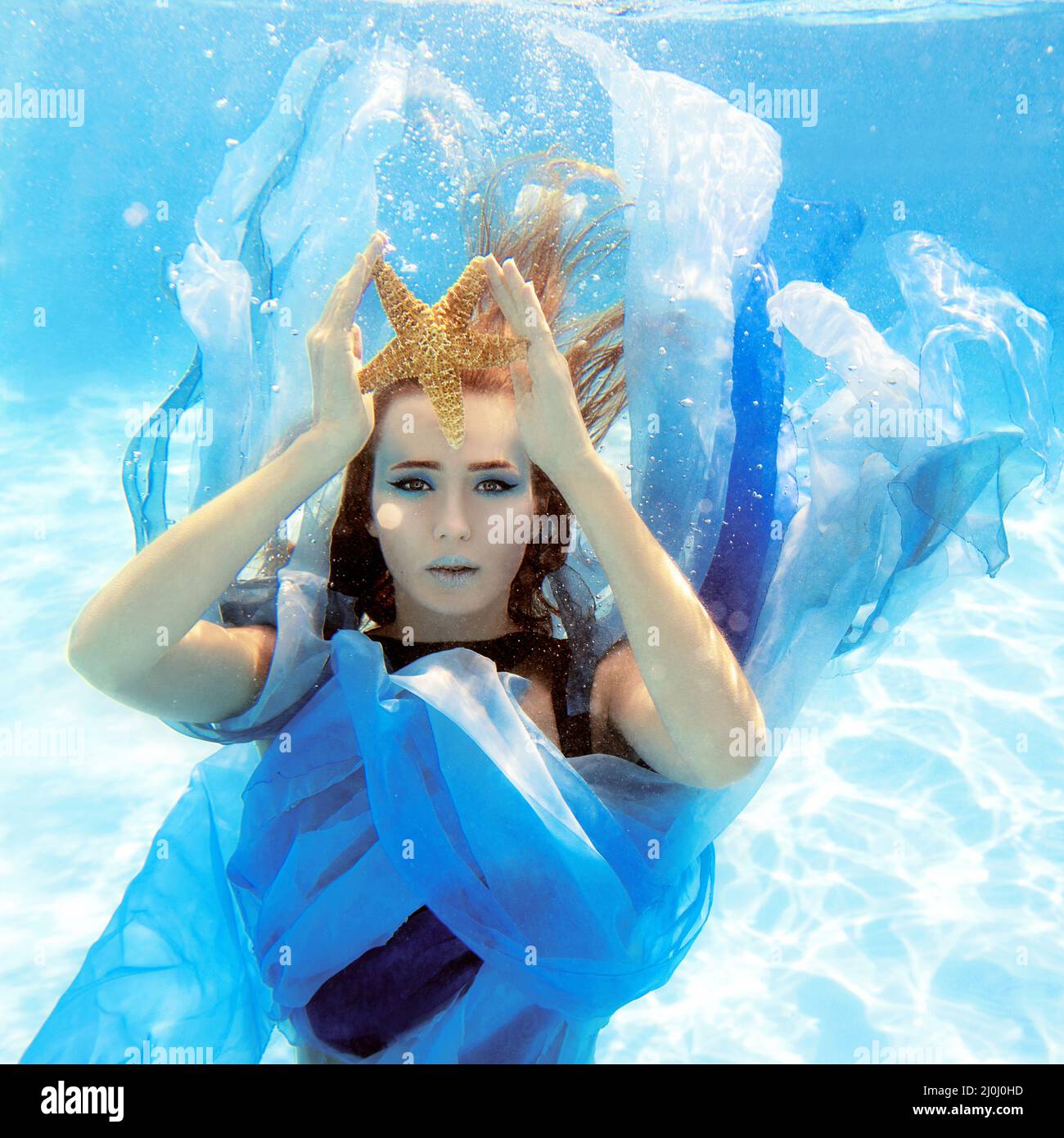 Ritratto subacqueo di moda di bella giovane donna in abito blu Foto Stock