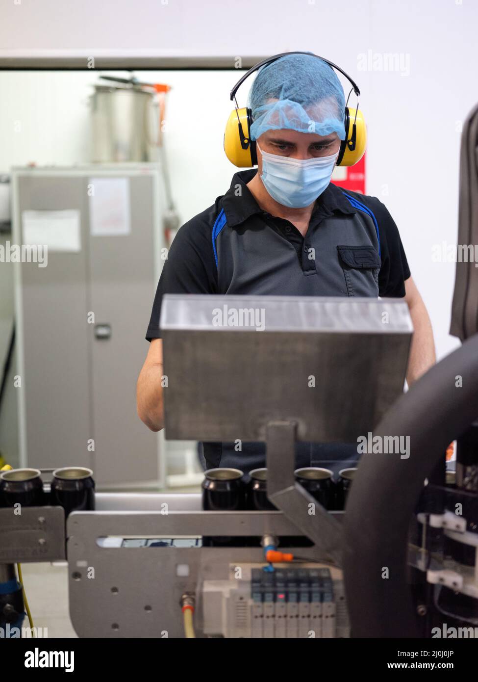 Foto verticale di un uomo che lavora su una macchina nella linea di produzione della lattina della birra Foto Stock