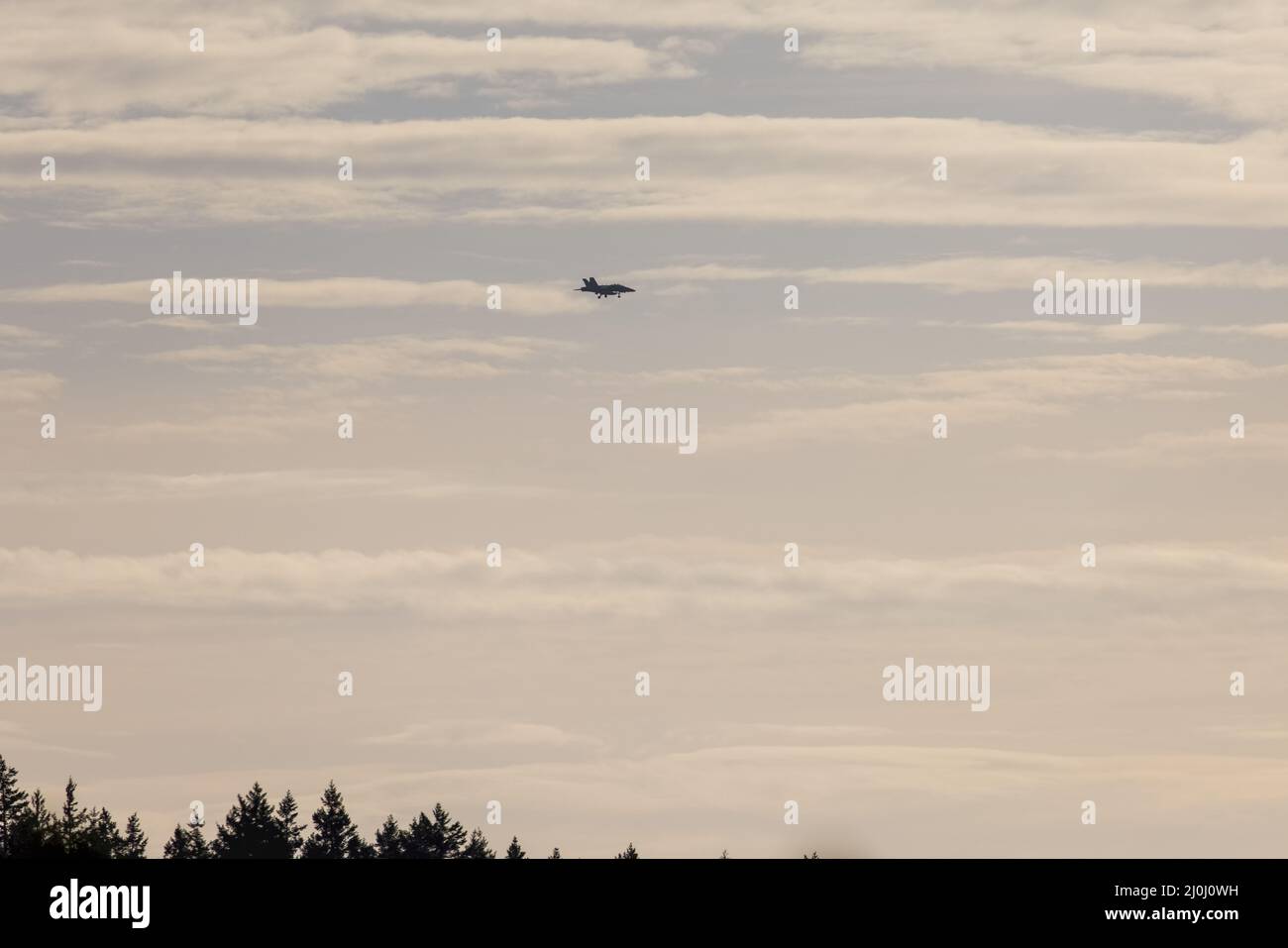 aereo da caccia che vola attraverso il cielo rosa e blu pastello Foto Stock