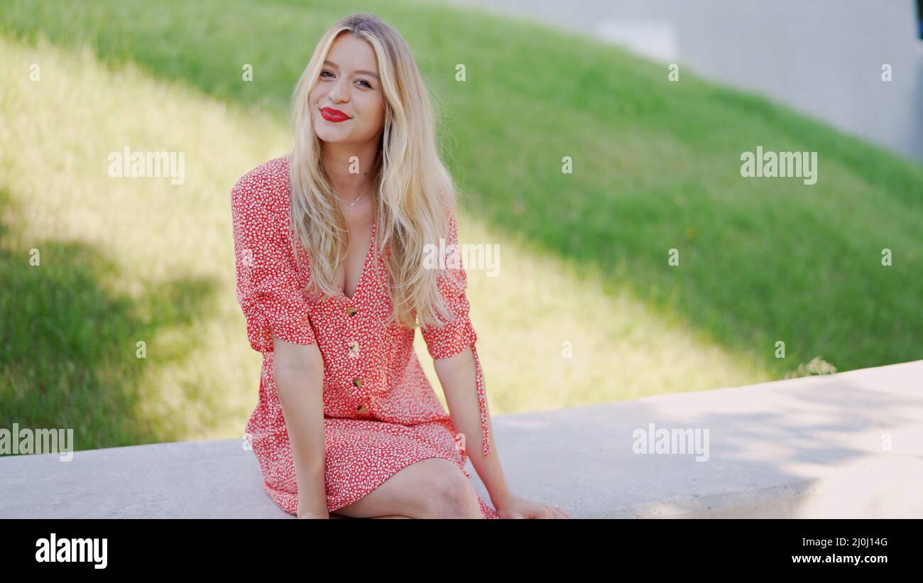 Positiva giovane donna seduta al confine nel parco Foto Stock