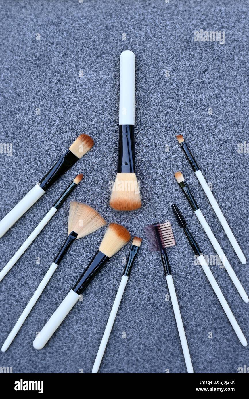 closeup il mazzo bianco marrone makeup kit spazzolare su sfondo grigio marrone fuori fuoco. Foto Stock
