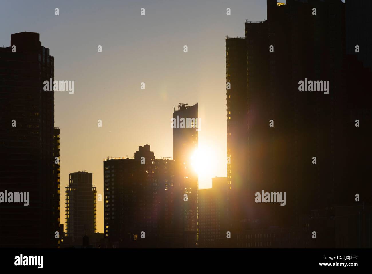 Il sole tramonta tra il grattacielo Midtown Manhattan oltre l'East River il 2021 novembre a New City. Vista dal Franklin D. Roosevelt Four Freedoms Park Foto Stock