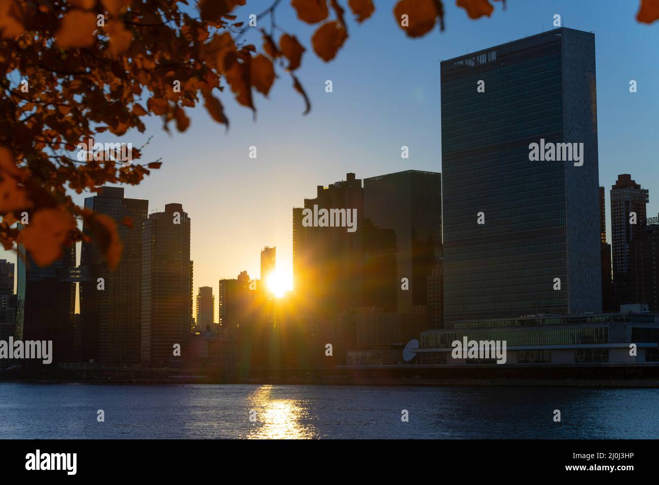 Il sole tramonta tra il grattacielo Midtown Manhattan oltre l'East River il 2021 novembre a New City. Vista dal Franklin D. Roosevelt Four Freedoms Park Foto Stock