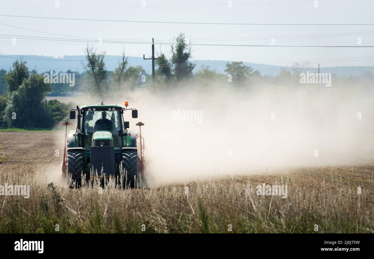 Trattore che aratura terreno agricolo secco in autunno Foto Stock