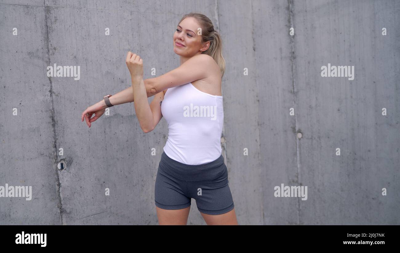 Felice sportswoman riscaldamento su strada Foto Stock