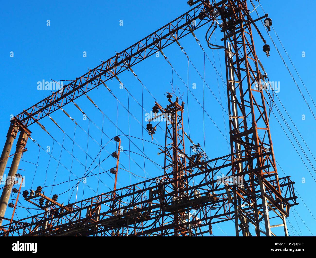 Rete elettrica ferroviaria con pali e fili di ferro su sfondo azzurro cielo chiaro Foto Stock