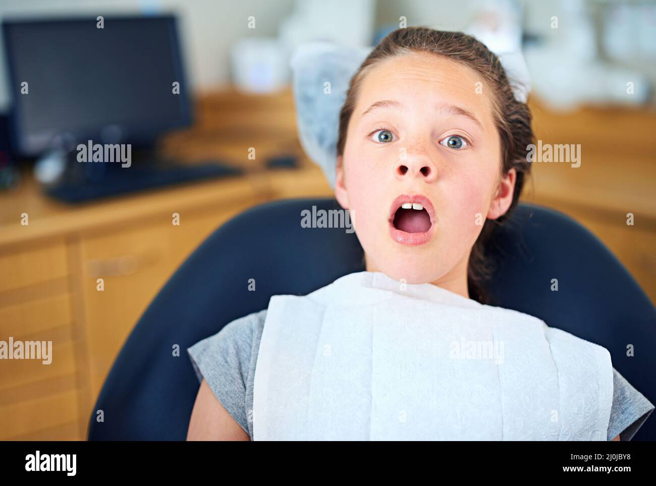 Nel sedile caldo. Scatto di una ragazza giovane che guarda terrorizzata mentre si siede in una sedia dentista. Foto Stock