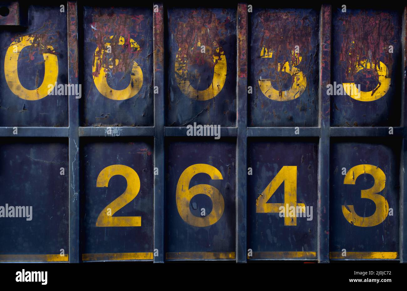 vista frontale di un contenitore intermodale in blu intenso con macchie arrugginite e cifre numeriche gialle grandi Foto Stock