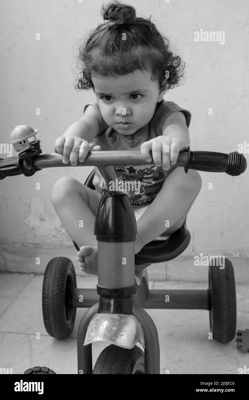 Carino ragazzo Shivaay che guida in bicicletta a casa balcone durante l'estate, dolce bambino fotoshoot durante la luce del giorno, ragazzo piccolo godere in bicicletta a ho Foto Stock