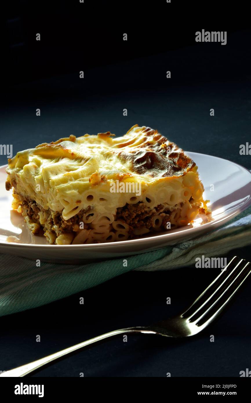 Pezzo di lasagna greca con salsa di carne e bechamel, noto come pastitsio e forchetta Foto Stock