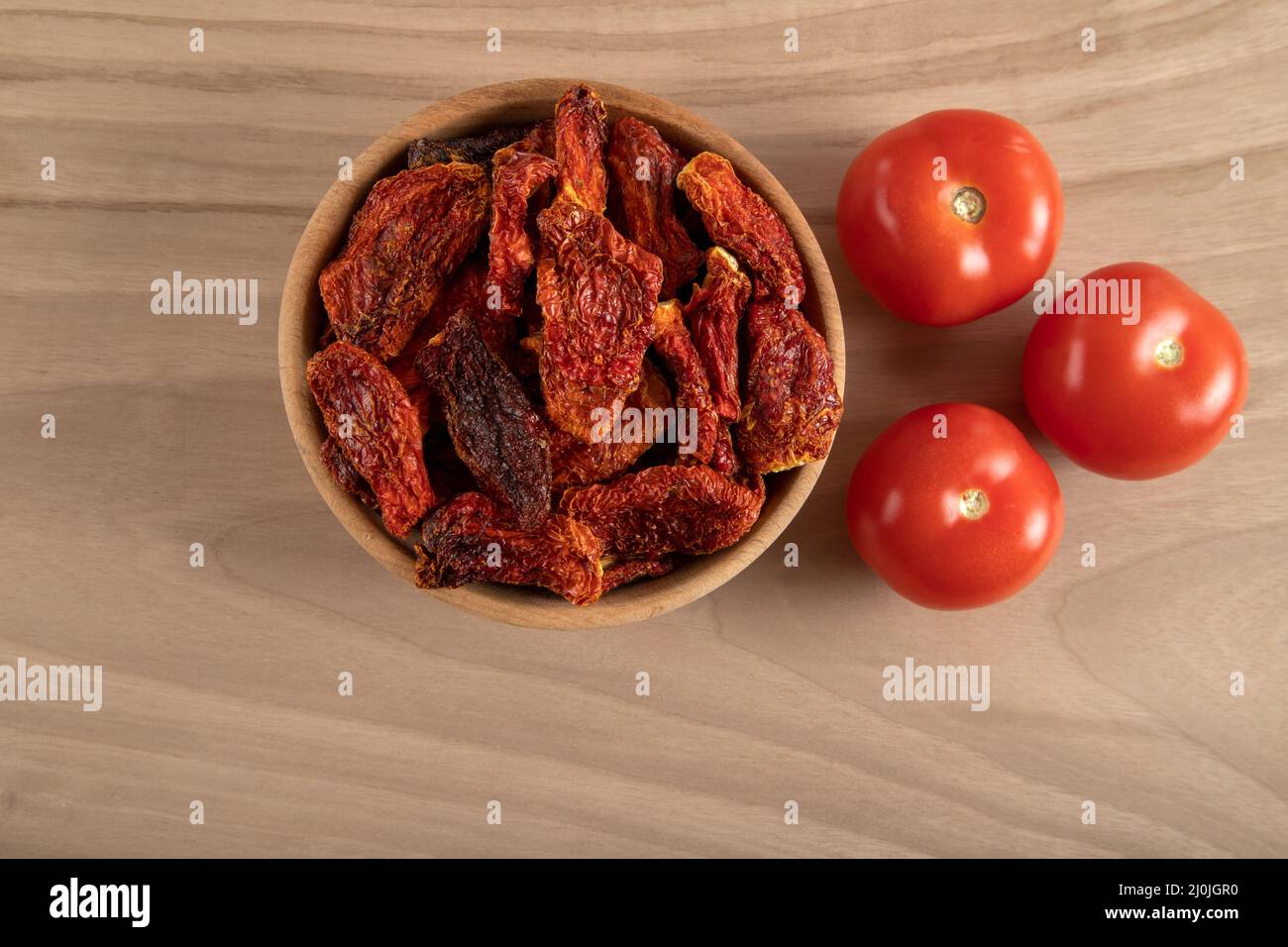 Pomodori freschi e pomodori secchi insieme su sfondo di legno Foto Stock