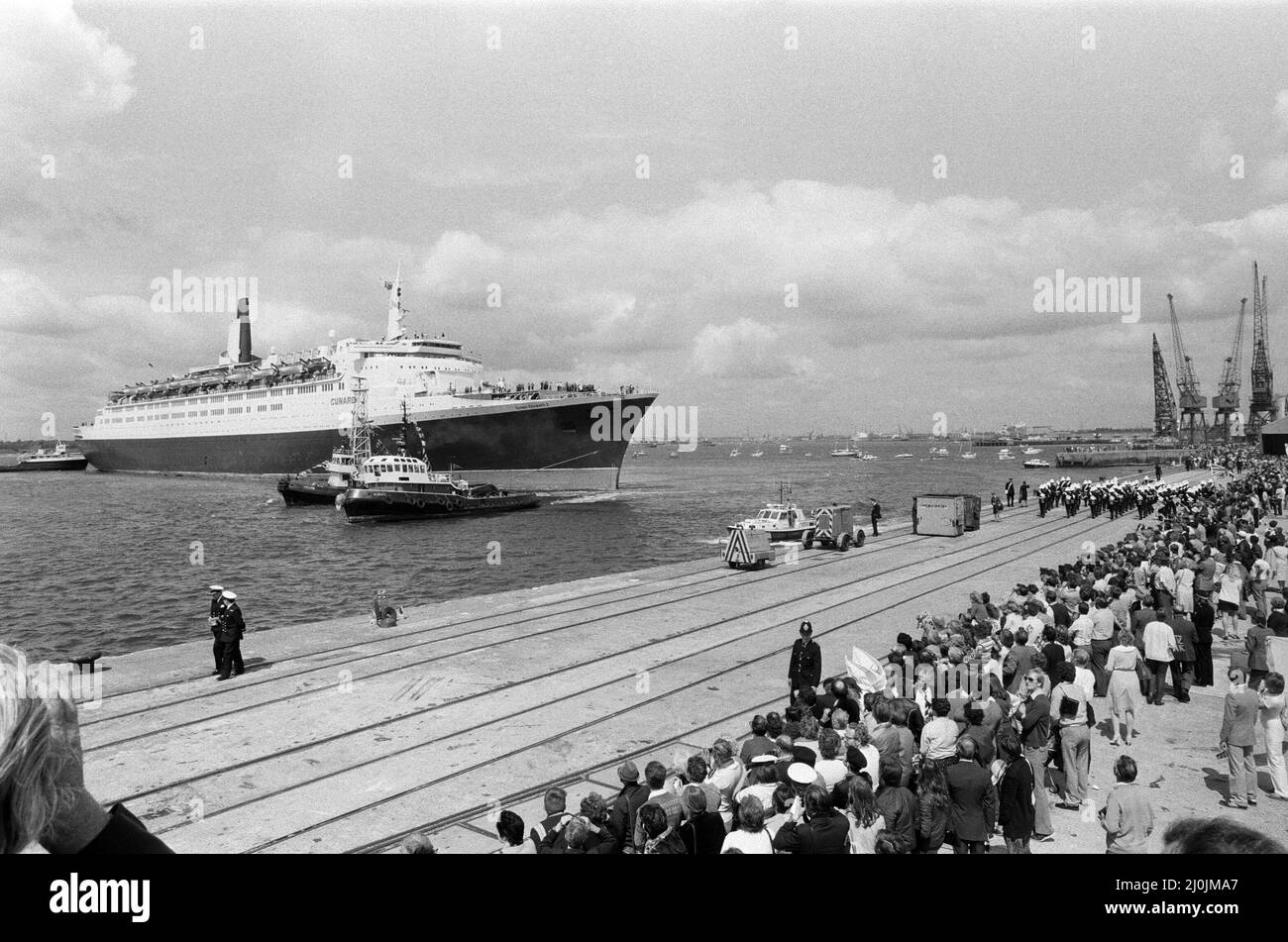 Il QE2 torna a casa a Southampton. Union Jacks è festooned sulle automobili, drappeggiato sulle spalle, ondulato sui bastoni. Southampton dà il benvenuto a "Three Cheers" al QE2 lussuoso liner trasformato in trooper di ritorno dalla guerra. A bordo è il suo prezioso carico, i 700 sopravvissuti della HMS Coventry, ardent e Antelope, affondati nella battaglia per le Falklands. 11th giugno 1982. Foto Stock