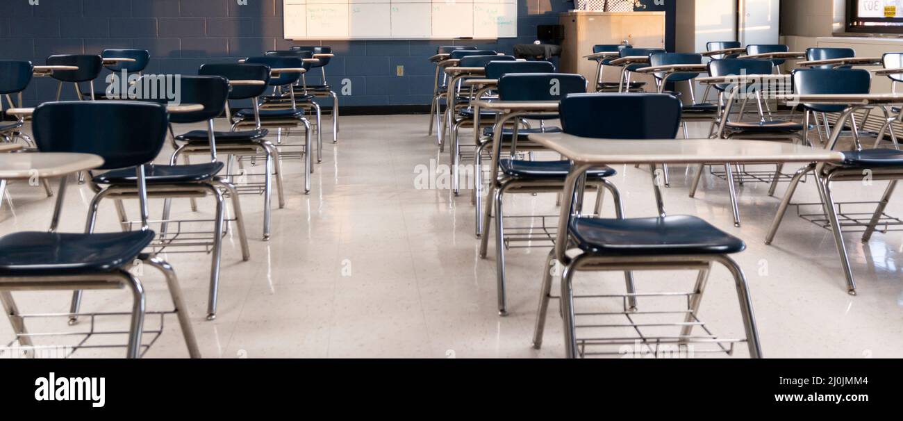 Un'aula vuota della scuola superiore con gli allievi scrivanie distanziate fuori per il distanziamento sociale. Foto Stock