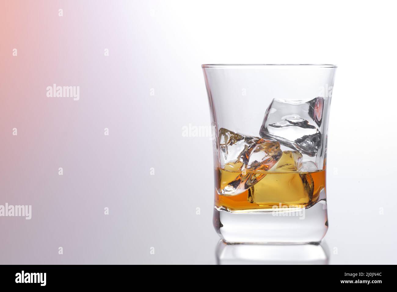 Bicchiere di whiskey color ambra scotch e ghiaccio su uno sfondo luminoso Foto Stock