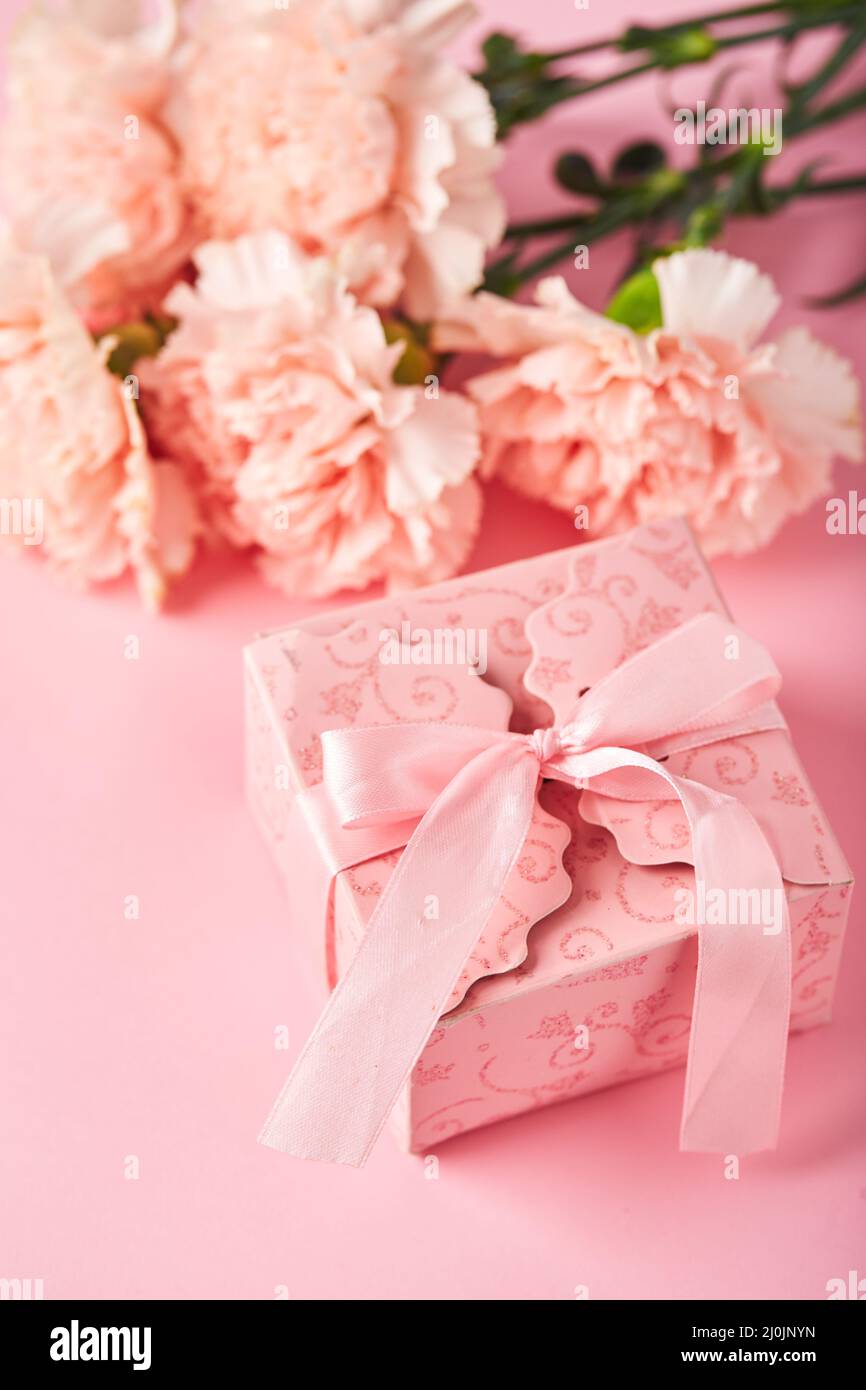 Bouquet di garofani rosa e scatola regalo rosa. Design concetto di saluto vacanza con bouquet garofano su sfondo rosa Foto Stock