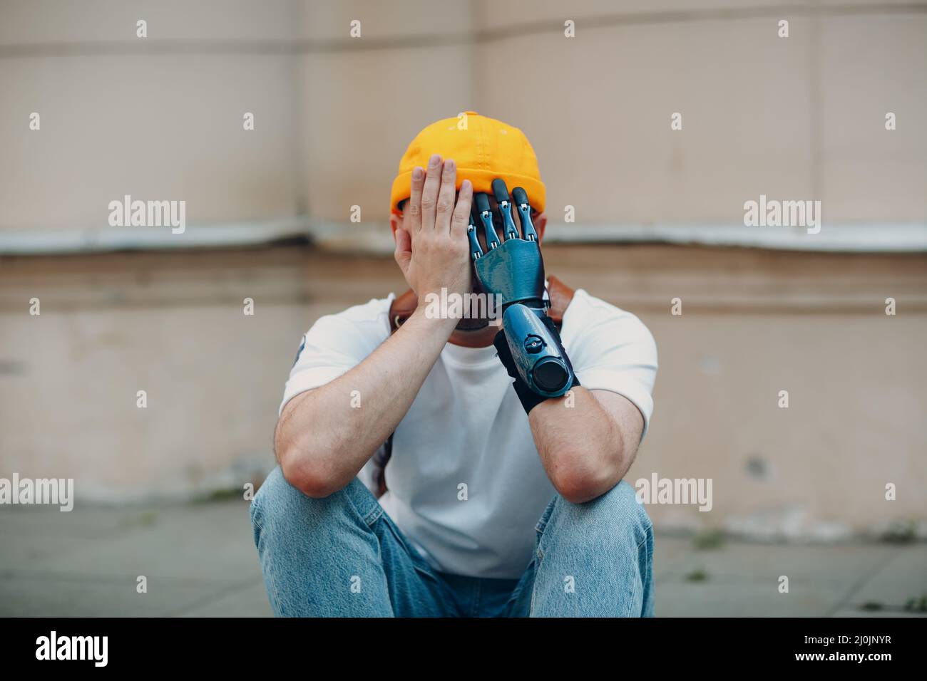 Giovane uomo disabile con mano protesica artificiale in abiti casual. Foto Stock