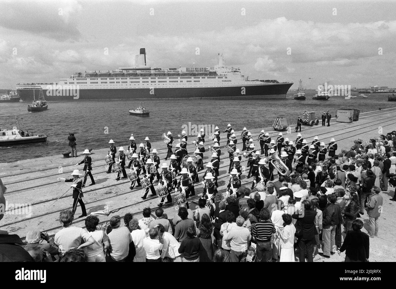 Il QE2 torna a casa a Southampton. Union Jacks è festooned sulle automobili, drappeggiato sulle spalle, ondulato sui bastoni. Southampton dà il benvenuto a "Three Cheers" al QE2 lussuoso liner trasformato in trooper di ritorno dalla guerra. A bordo è il suo prezioso carico, i 700 sopravvissuti della HMS Coventry, ardent e Antelope, affondati nella battaglia per le Falklands. 11th giugno 1982. Foto Stock
