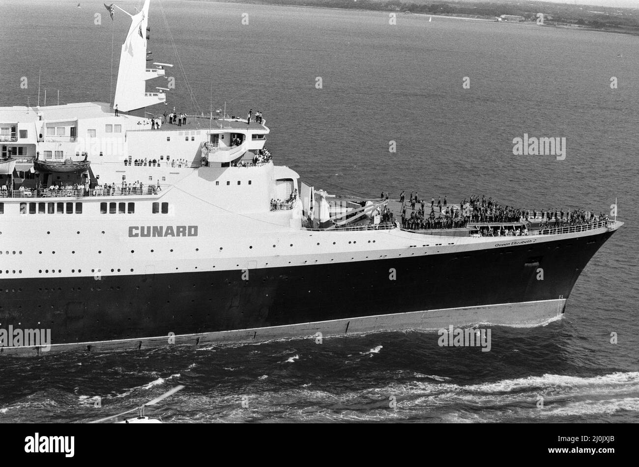 Il QE2 torna a casa a Southampton. Union Jacks è festooned sulle automobili, drappeggiato sulle spalle, ondulato sui bastoni. Southampton dà il benvenuto a "Three Cheers" al QE2 lussuoso liner trasformato in trooper di ritorno dalla guerra. A bordo è il suo prezioso carico, i 700 sopravvissuti della HMS Coventry, ardent e Antelope, affondati nella battaglia per le Falklands. 11th giugno 1982. Foto Stock