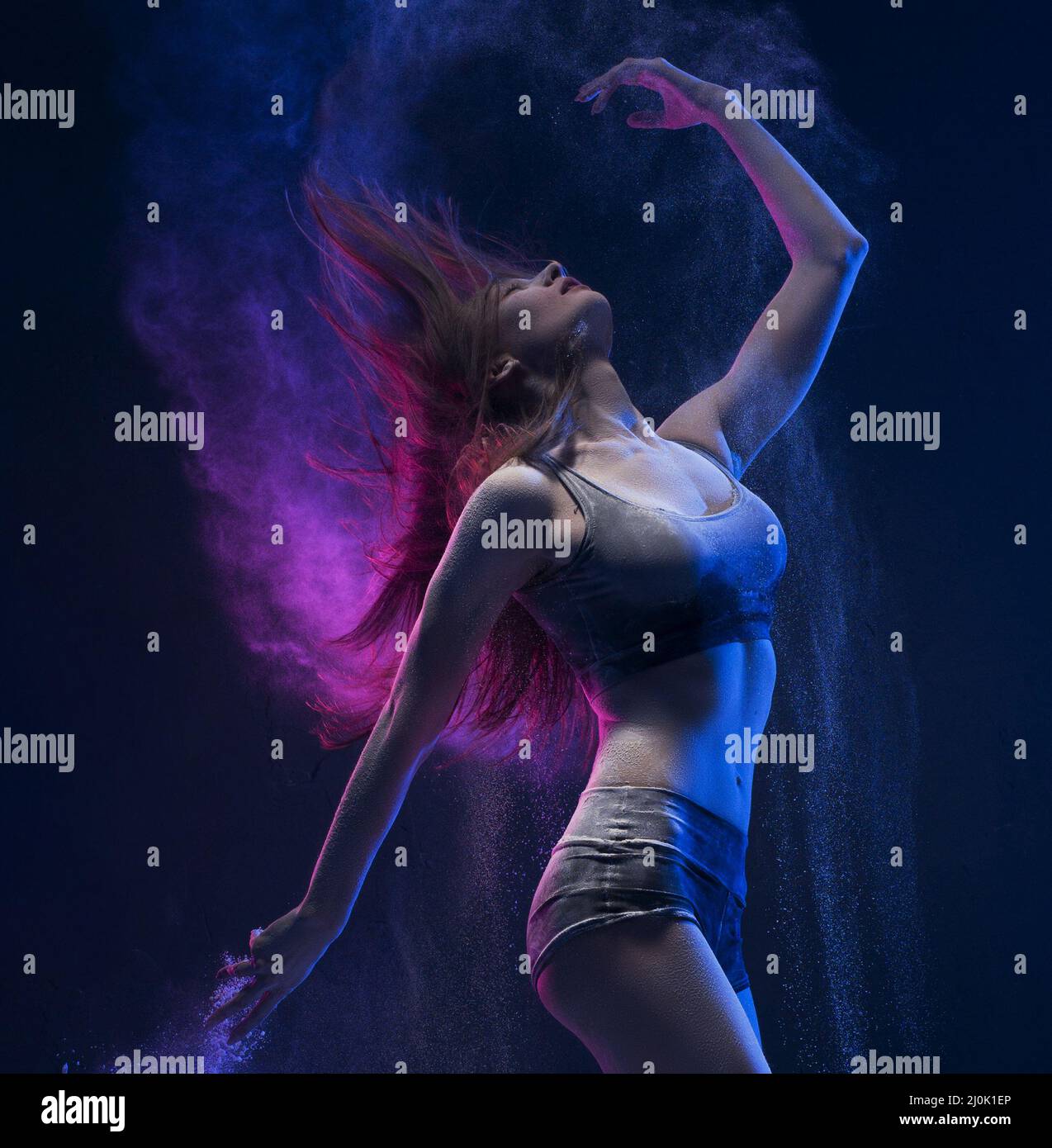 Slim girl dancing in blu di una nube di polvere di vista di profilo Foto Stock