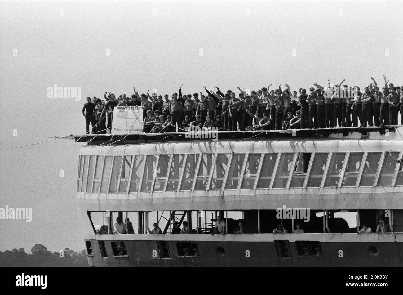 Il QE2 torna a casa a Southampton. Union Jacks è festooned sulle automobili, drappeggiato sulle spalle, ondulato sui bastoni. Southampton dà il benvenuto a "Three Cheers" al QE2 lussuoso liner trasformato in trooper di ritorno dalla guerra. A bordo è il suo prezioso carico, i 700 sopravvissuti della HMS Coventry, ardent e Antelope, affondati nella battaglia per le Falklands. 11th giugno 1982. Foto Stock