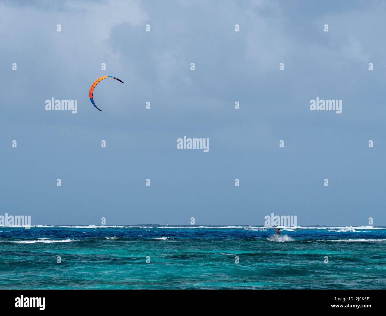 San Andres, Colombia - Novembre 17 2021: Uomo marrone Kitesurfing nel mare con un Kiteboarding colorato Foto Stock