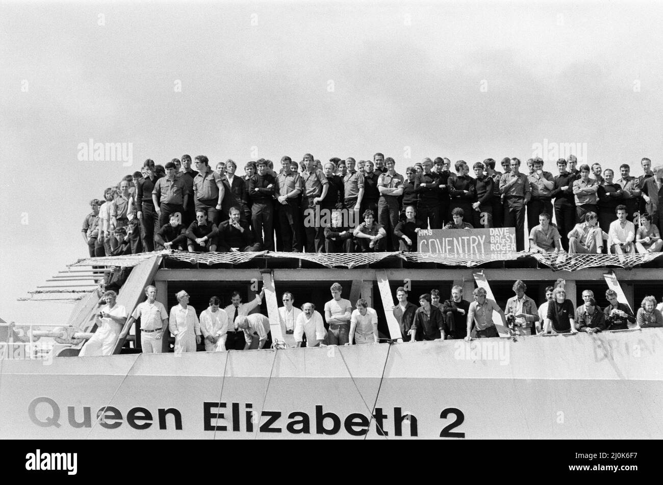 Il QE2 torna a casa a Southampton. Union Jacks è festooned sulle automobili, drappeggiato sulle spalle, ondulato sui bastoni. Southampton dà il benvenuto a "Three Cheers" al QE2 lussuoso liner trasformato in trooper di ritorno dalla guerra. A bordo è il suo prezioso carico, i 700 sopravvissuti della HMS Coventry, ardent e Antelope, affondati nella battaglia per le Falklands. 11th giugno 1982. Foto Stock