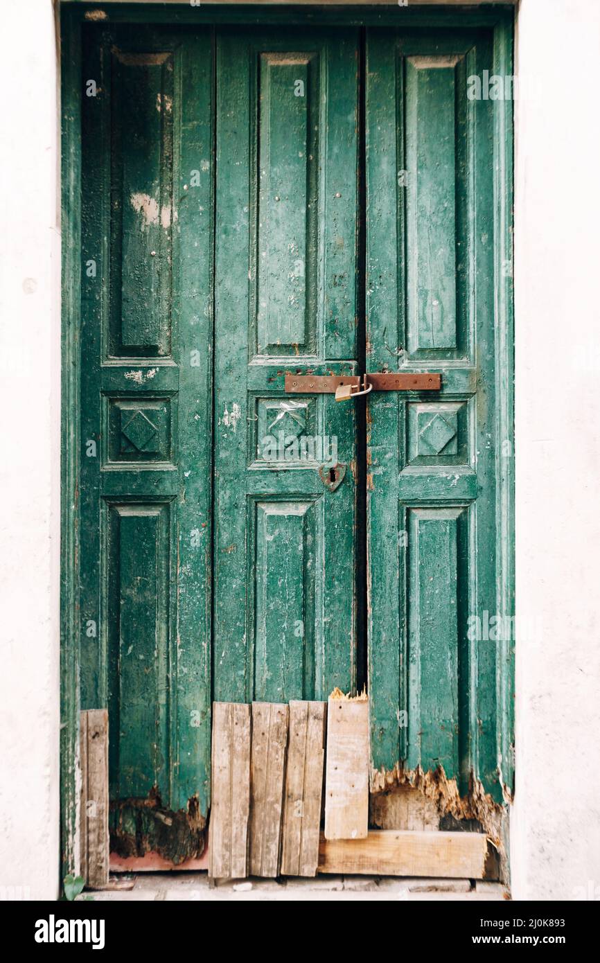 Primo piano di porte in legno verde fiabdo chiuse con un fondo rotto e tavole all'ingresso. Foto Stock