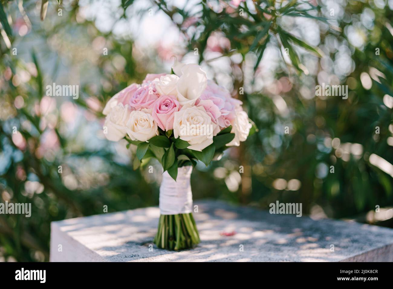 Bouquet nuziale di rose di rosa e crema e calla gigli ferrovia in pietra bianca vicino alla fiorente rosa oleandro cespuglio Foto Stock