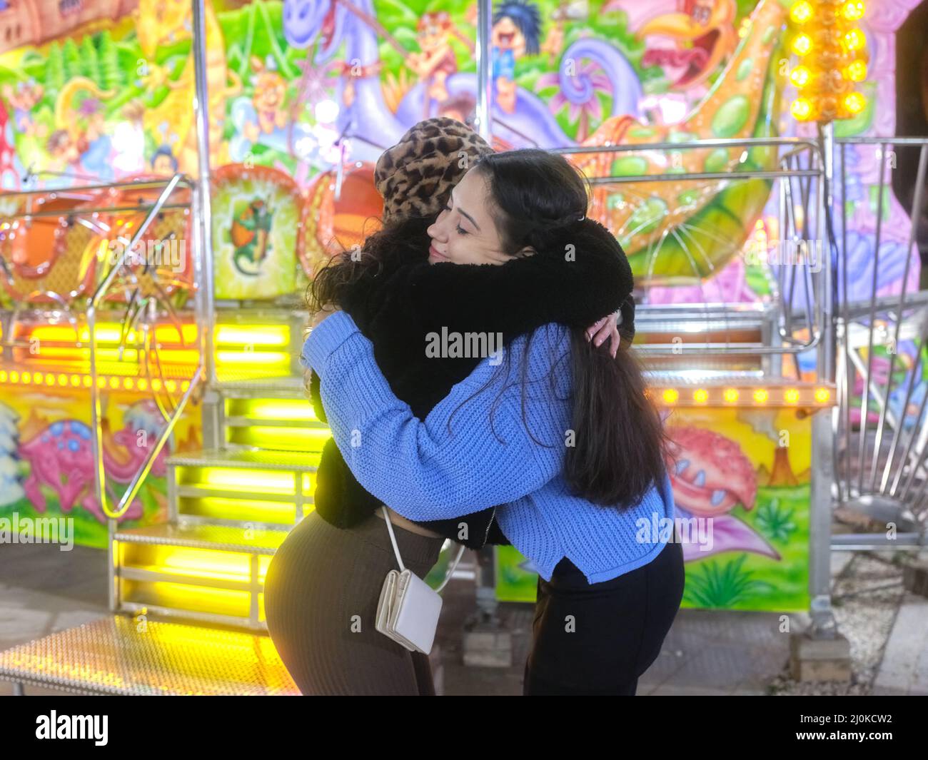 Due amici si abbracciano in una fiera notturna Foto Stock