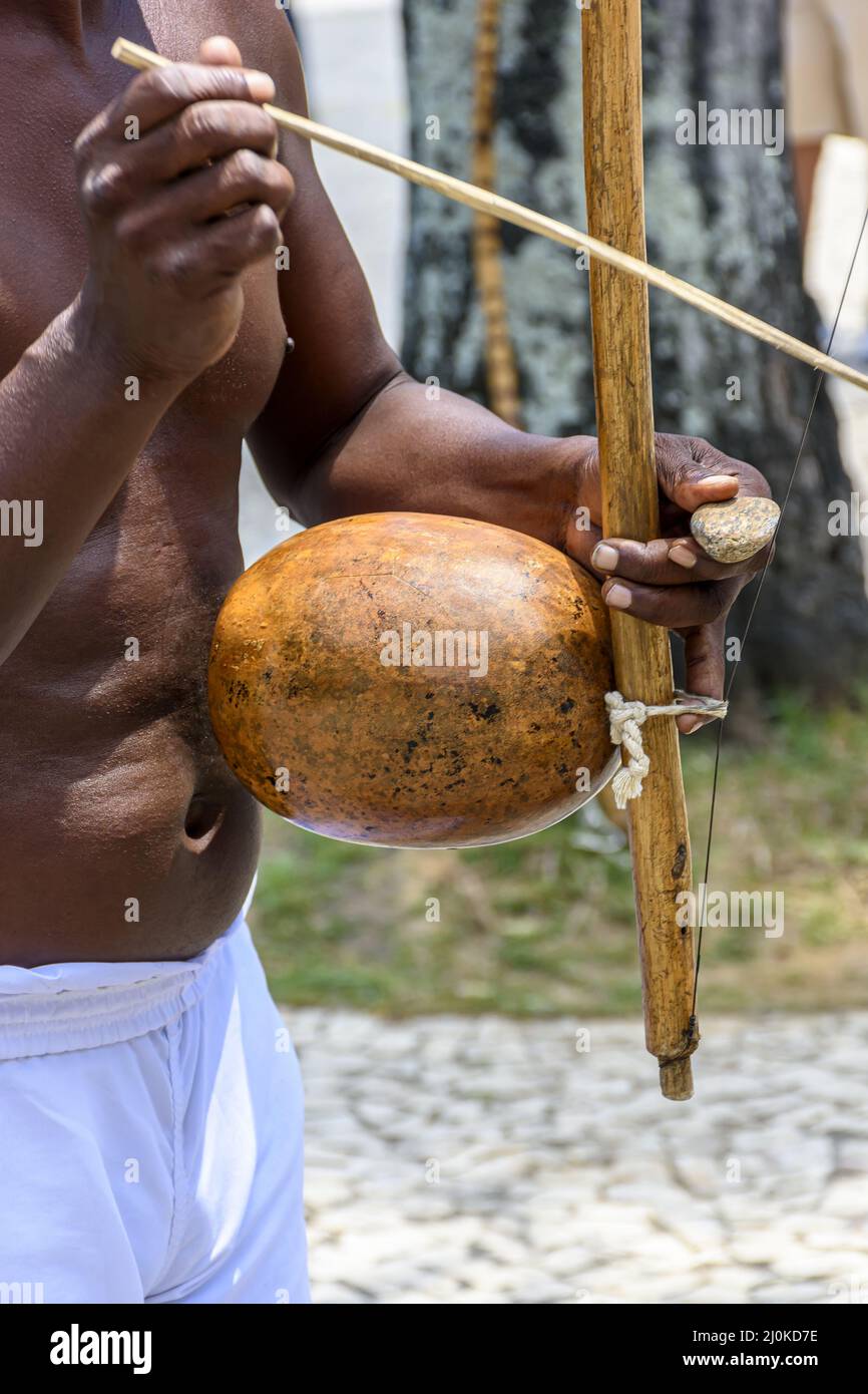 Musicista che suona un tradizionale strumento di percussione brasiliano chiamato berimbau durante uno spettacolo di capoeira Foto Stock