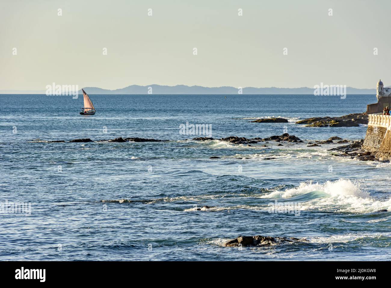 Rudimentale barca da pesca che naviga all'orizzonte durante il tramonto in All Saints Bay nella città di Salvador Foto Stock