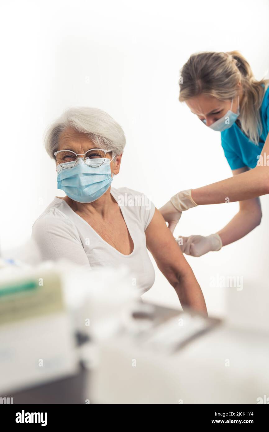 Colpo verticale di donna anziana caucasica che ottiene un richiamo di vaccino per aiutare a fermare la pandemia. Foto di alta qualità Foto Stock
