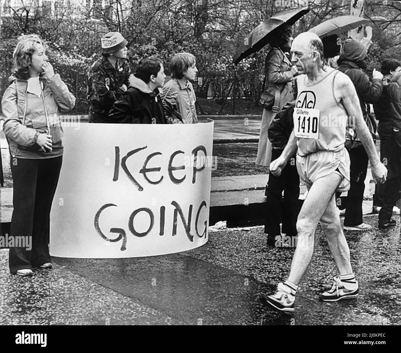 Un concorrente nella prima maratona di Londra, marzo 1981.George Douthwaite a passo di cammino passando un cartello che dice 'continuare' Foto Stock
