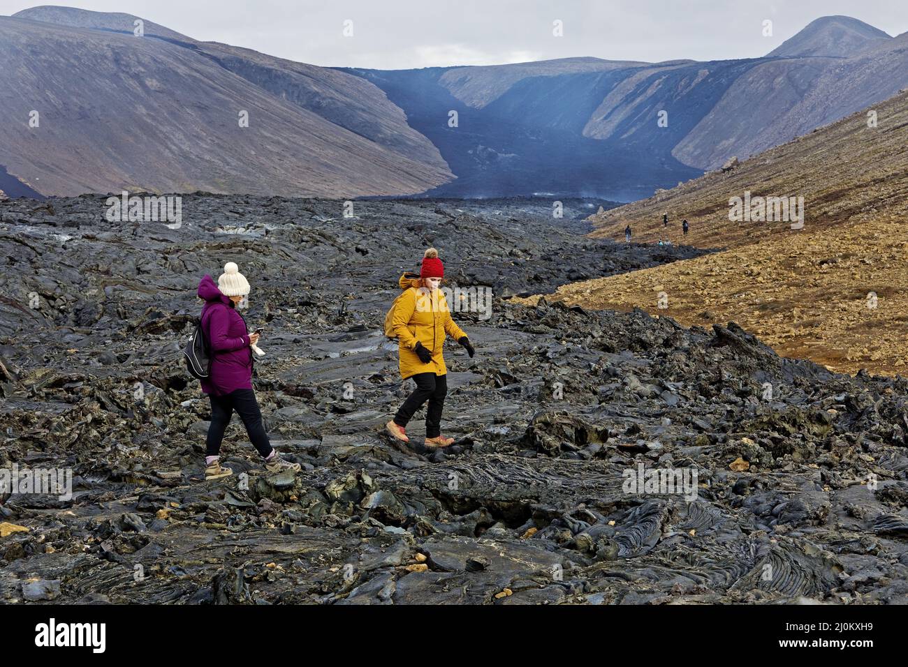La gente cammina sul paesaggio di lava vulcanica appena eruttata, Fagradersfjall, penisola di Reykjanes, Islanda Foto Stock