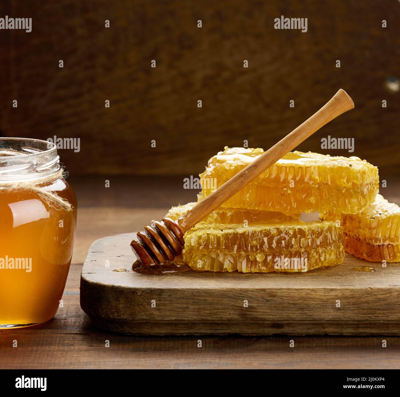 Nido d'ape in cera con miele su tavola di legno e cucchiaio di legno, tavola marrone Foto Stock