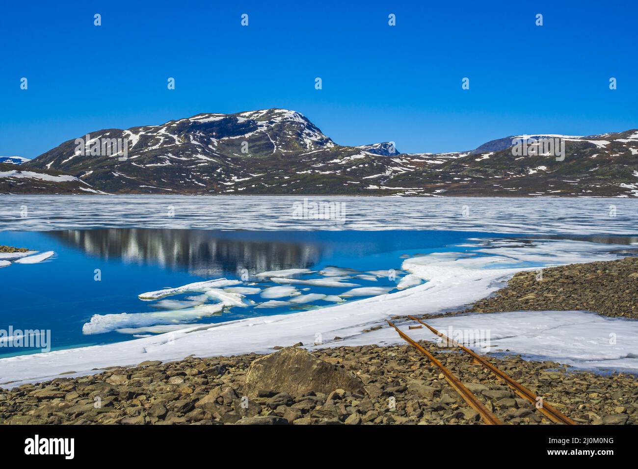 Vecchie rotaie conducono in acqua del lago congelato Vavatn Hemsedal. Foto Stock