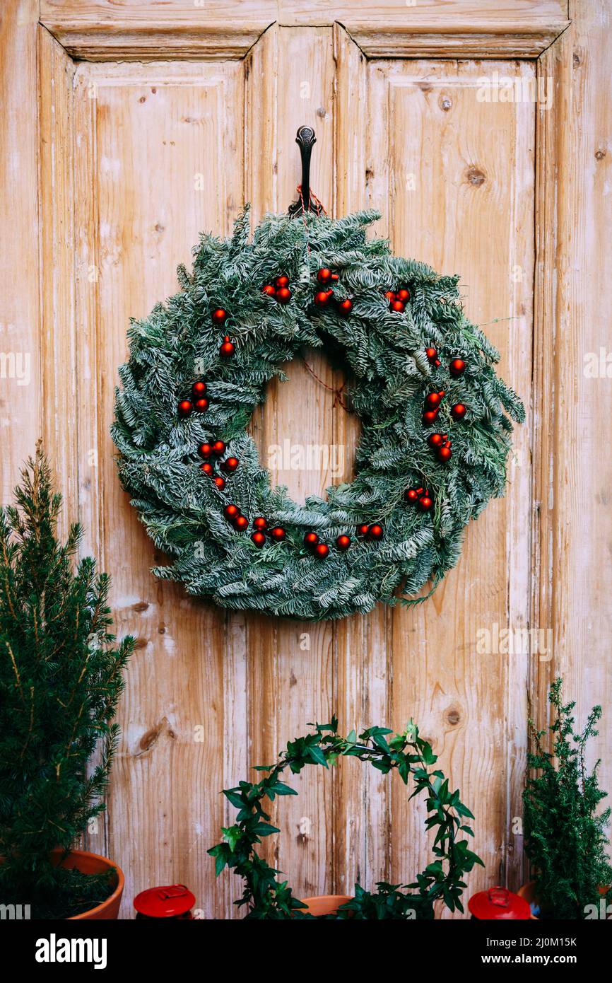 Corona di Natale di rami di abete su una porta di legno. Foto Stock