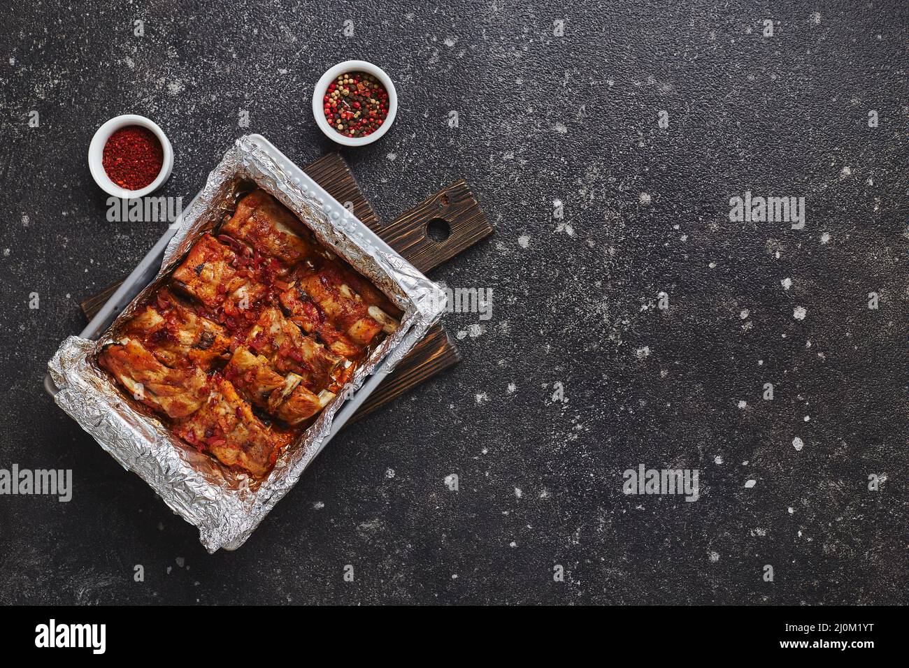 Costolette di maiale arrosto in foglio di alluminio in una teglia da forno in metallo. Concetto di cibo americano. Vista dall'alto, spazio di copia Foto Stock