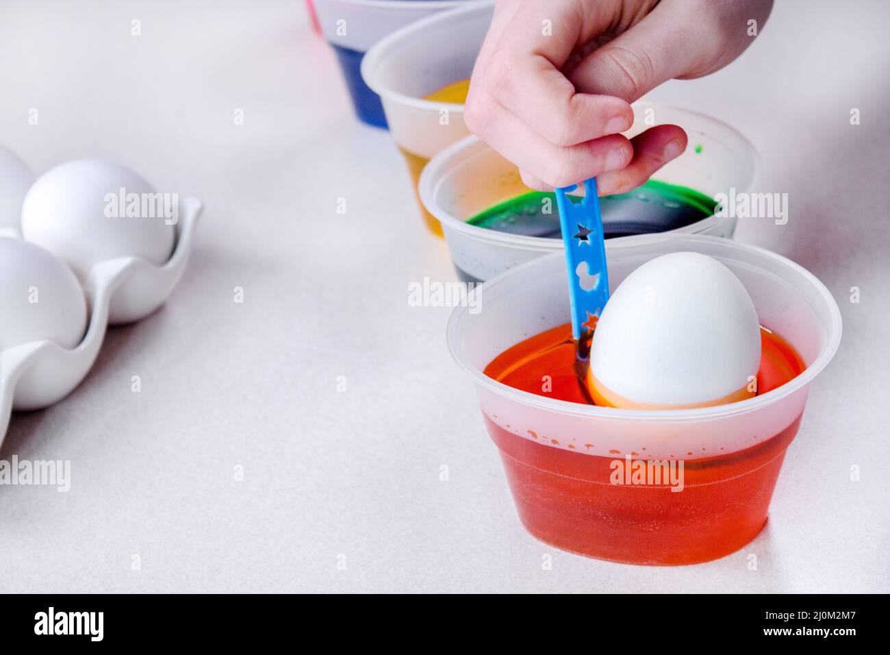 La mano del capretto dipinge le uova per le feste di pasqua. Tintura uova di pasqua a casa. Il bambino crea decorazioni natalizie. Foto Stock