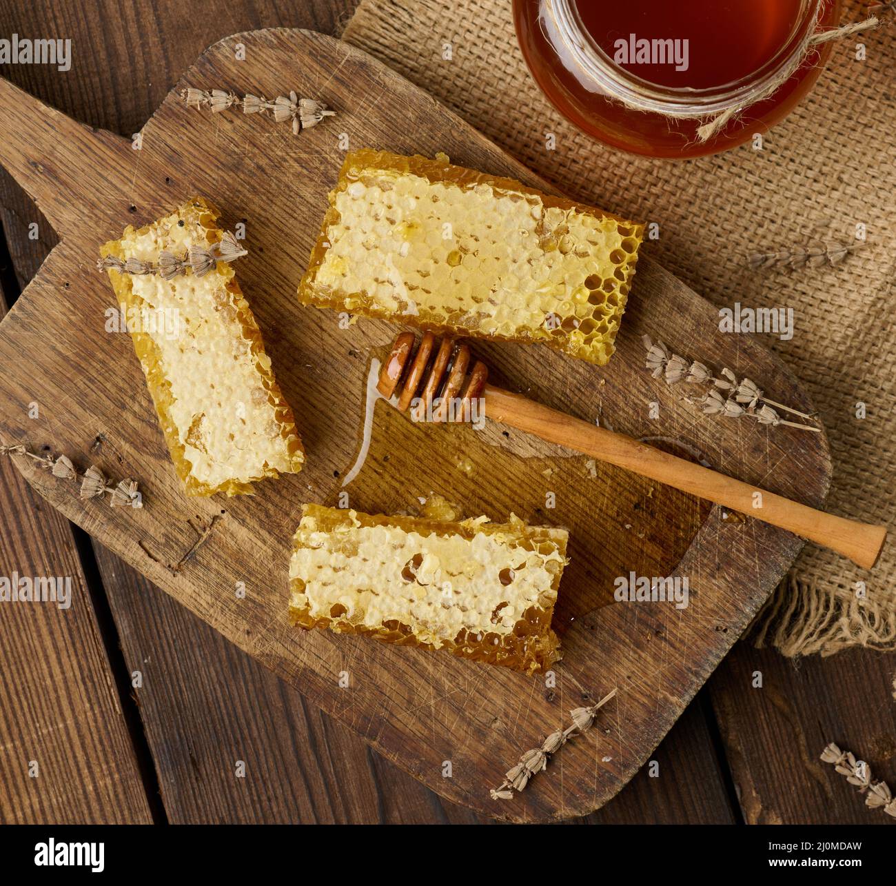 Nido d'ape in cera con miele su tavola di legno e cucchiaio di legno, tavolo marrone, vista dall'alto Foto Stock
