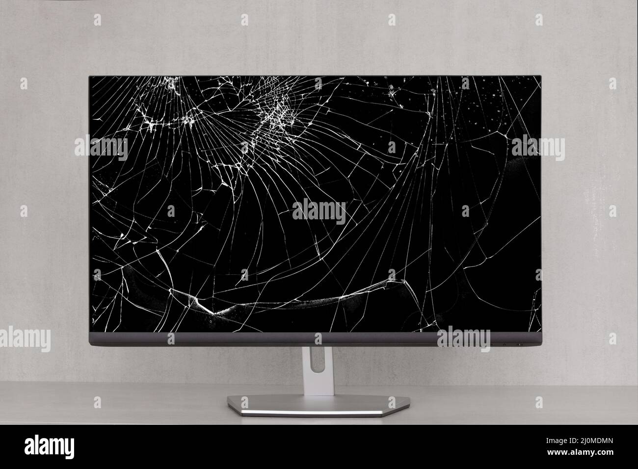 Monitor del computer con uno schermo rotto in crepe su sfondo grigio primo piano Foto Stock