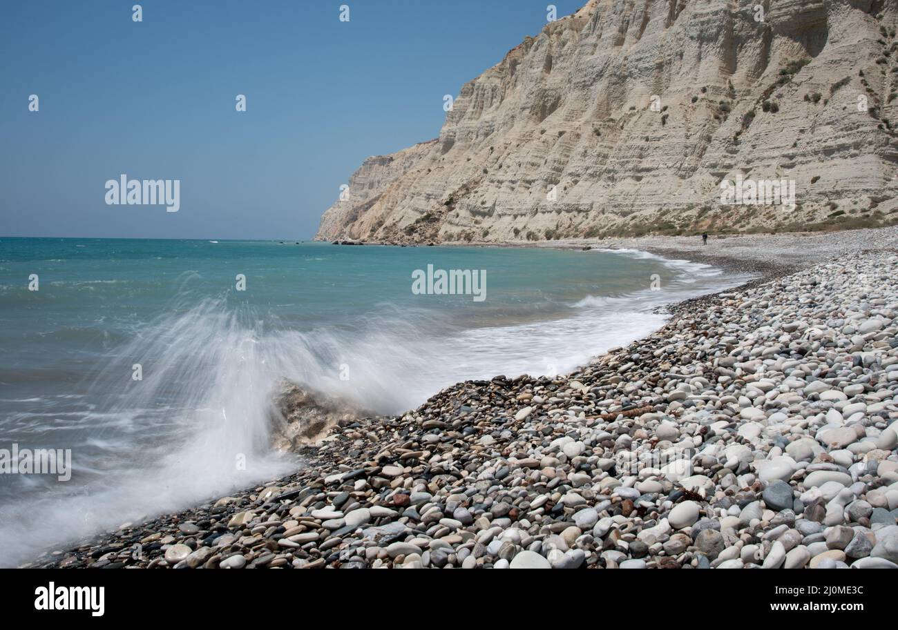 Spiaggia tropicale di ghiaia vuota sotto le scogliere bianche contro il cielo blu. Foto Stock