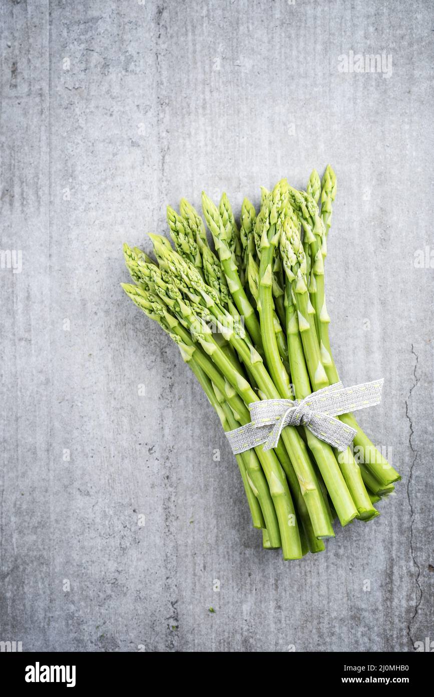 Riga verde Asparagus come primo piano su sfondo grigio con spazio di copia a sinistra Foto Stock