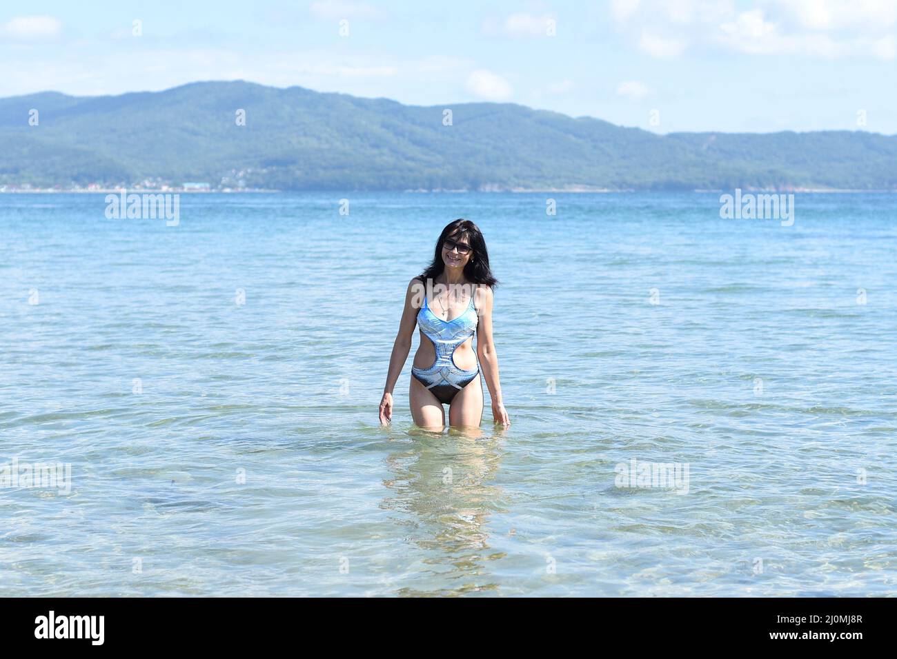 Donna russa di 45 anni in costume da bagno che ride e sta in piedi nel mare giapponese Foto Stock