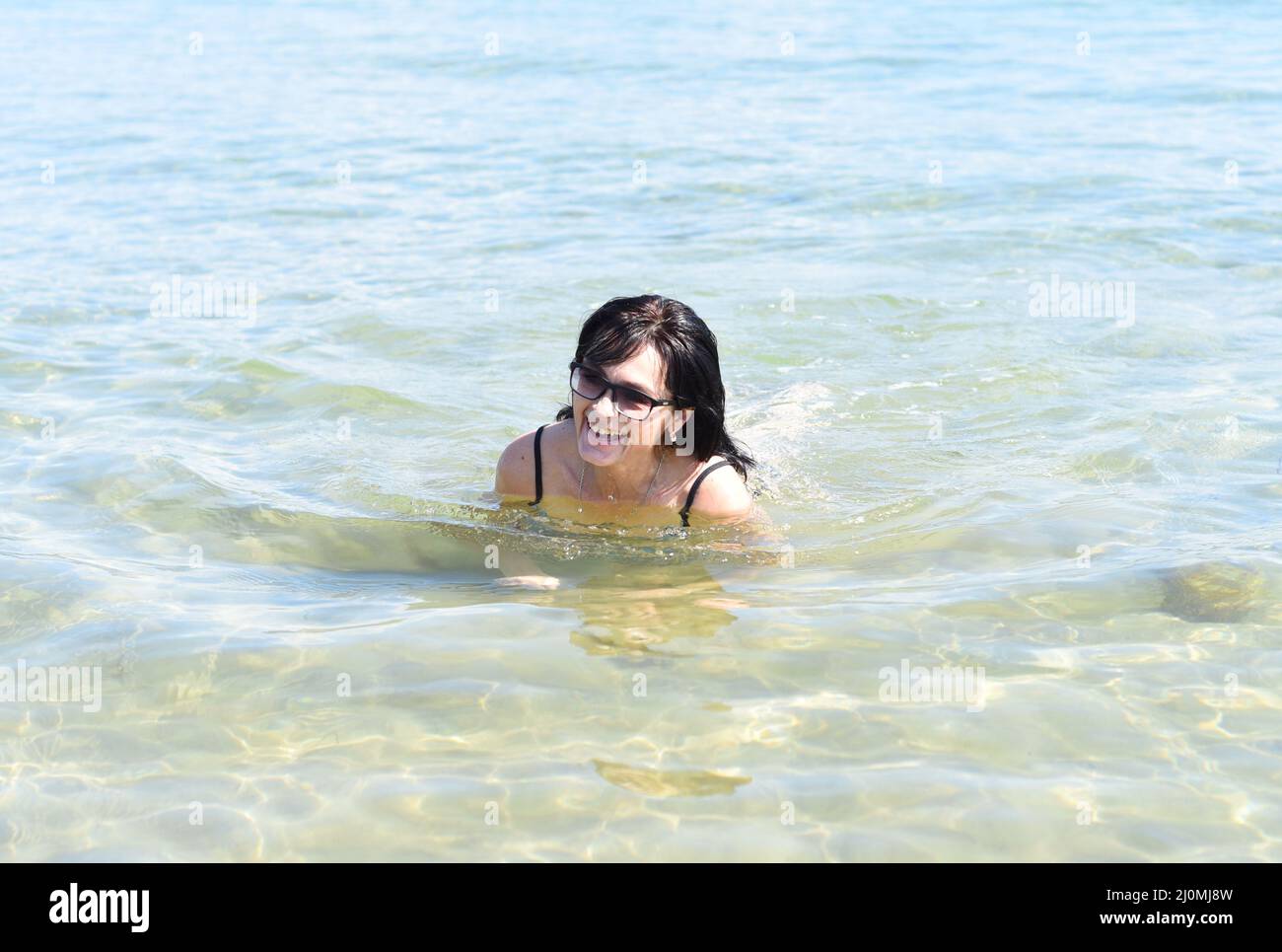 Donna russa di 45 anni in costume da bagno che ride e sta in piedi nel mare giapponese Foto Stock
