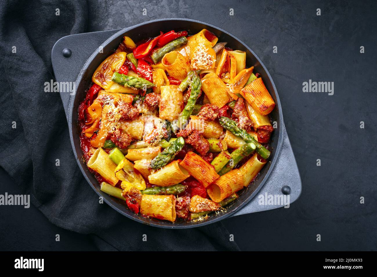 Tradizionale pasta italiana arrostita mezzi paccheri rigati con salsiccia salsiccia con punte di asparagi verdi in salsa di pomodoro servito a. Foto Stock